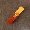A leather duduk reed case by Dudukhouse, shown open on a textured gray felt background. The exterior is a warm reddish-brown leather, while the interior lining and the visible wooden insert are a light tan.